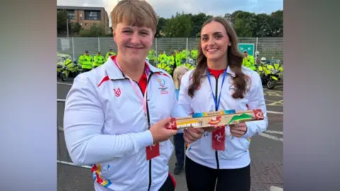ERICA BELLHOUSE Alfie and Laura wearing IOM team tracksuits and holding the Manx baton.