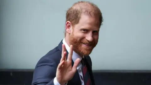 Prince Harry smiles and waves as he arrives at court on Wednesday
