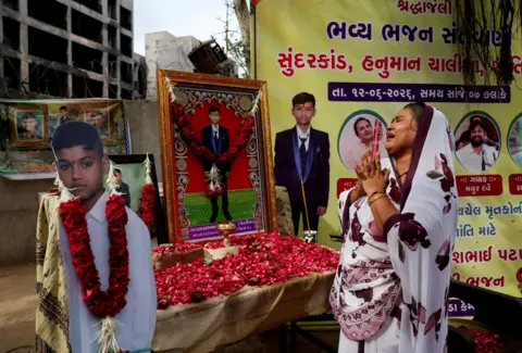 Reuters Sitaben Patni, a survivor and the mother of Akash Patni, 14, who died in an Air India Boeing 787-8 Dreamliner crash on June 12, 2025, mourns in front of her son’s portrait near the crash site during the first anniversary in Ahmedabad,