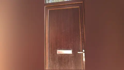 Carran O'Grady/LDRS Brown wooden front door speckled with dust.