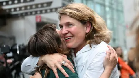 Reuters Mr Lliuya's lawyer, Roda Verheyen, can be seen smiling and embracing a woman outside the court in Hamm.