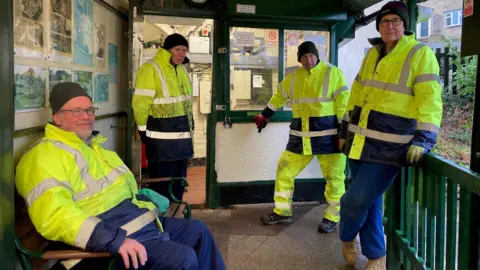 Four men in fluorescent yellow and blue jackets and trousers