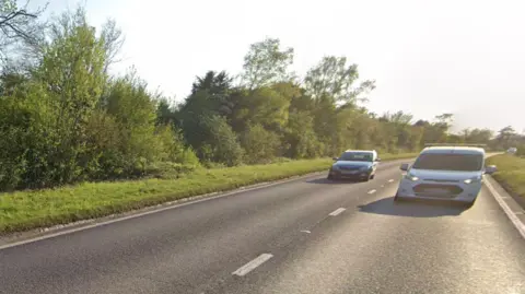 Two cars drive down the A31 Hogs Back at Puttenham, near Guildford.