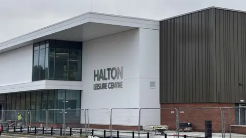 Halton Borough Council An exterior view of the the new white and brown building with a sign made from silver lettering which reads Halton Leisure Centre 