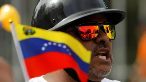 Reuters Een motorrijder houdt een Venezolaanse vlag vast vóór de laatste campagnebijeenkomst van de Venezolaanse presidentskandidaat Edmundo Gonzalez, in Caracas, Venezuela, 25 juli 2024.