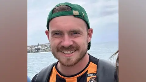 Jack Gorbert Jack Gorbert pictured wearing a Hull City shirt and a green baseball cap. There is an expanse of water in the background.