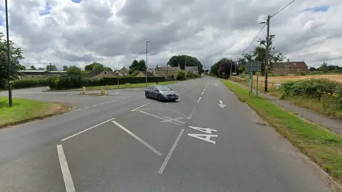 Google A lone car uses the junction of the A4 and Bradford Road in Corsham. Trees, fields and street furniture appears in the background.