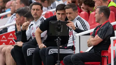 Tommy Elphick, Andoni Iraola and Shaun Cooper on the Liverpool bench