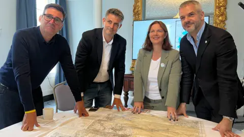 Four people gathered around a round table with a map on it of the Peak District 