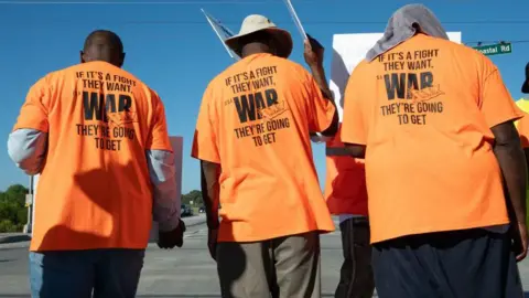 Getty Images Los trabajadores hacen un piquete frente al puerto de Savannah en Savannah, Georgia, el jueves.