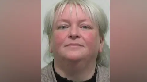 Mugshot of Thompson. She has silvery white hair tied back behind her head.