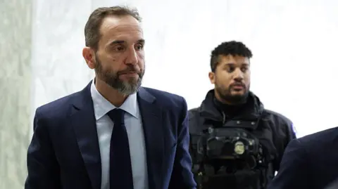Getty Images Former Special Counsel Jack Smith (left) arrives on Capitol Hill to testify about his criminal investigations of Donald Trump. He wears a navy blue suit.