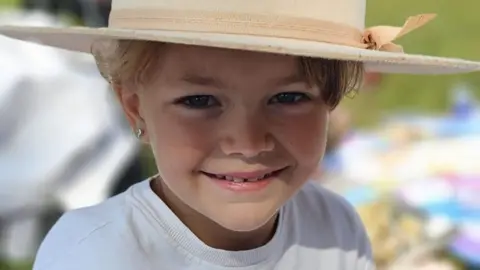 Collect/PA Real Life Ruby is wearing a white t-shirt and wearing a wide brimmed hat