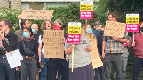 Around 10 people holding up anti-racism banners and chanting