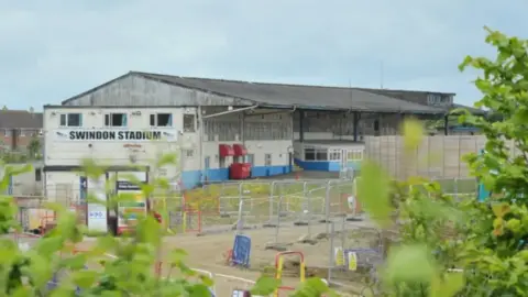 LDRS A building which says "Swindon Stadium" with scaffolding outside it.