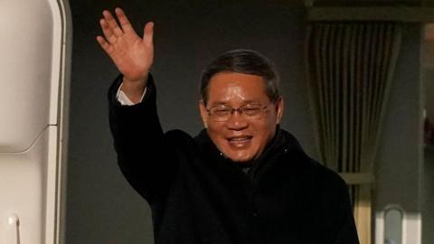 Li Qiang waves from the door of his plane after it arrives at Dublin Airport