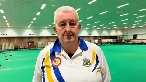 A man wearing a white shirt with grey hair 