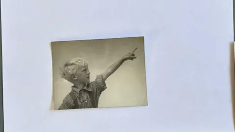 Absolutely Nice Vintage A black and white photograph of a boy with blond hair pointing into the sky.