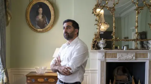 PA Media Reflective-looking image of former First Minister Humza Yousaf looking off to the window in front of the fireplace in Bute House, the first minister's residence.