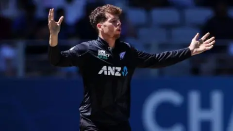 New Zealand's Mitchell Santner holds his arms out wide after bowling