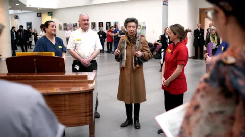 PA Media Princess Anne standing with health professionals through the main atrium in Southmead Hospital