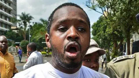 An archive headshot of Boniface Mwangi with his mouth open as he is being arrested during a demonstration.