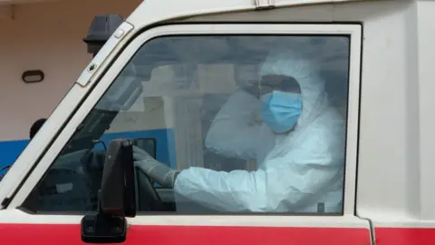 A doctor wearing personal protective equipment sits in an ambulance at the Ebola Virus Disease Treatment Center at the Bunia General Reference Hospital. 