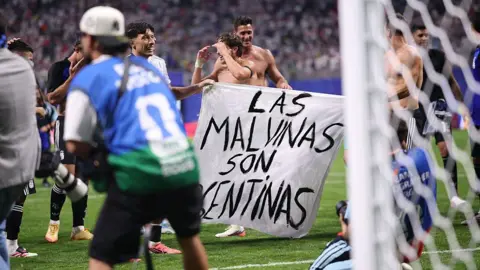 Getty Images Argentina's players display a banner reading ''Las Malvinas son Argentinas'' during the FIFA World Cup semi-final match between England and Argentina at the AKA Mercedes-Benz Stadium in Atlanta, United States, on July 15, 2026. 