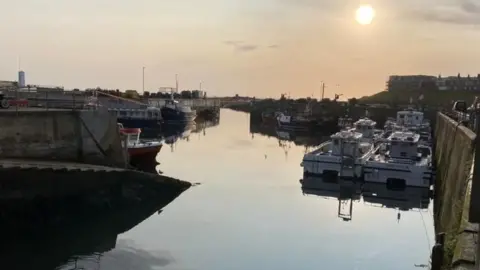 The harbour at Seahouses at sunset with boats used for day trips and fishing moored up