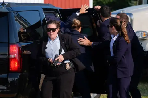 AP Republican presidential candidate former President Donald Trump is surrounded by U.S. Secret Service agents as he is taken to a vehicle at a campaign rally, Saturday, July 13, 2024, in Butler, Pa. 