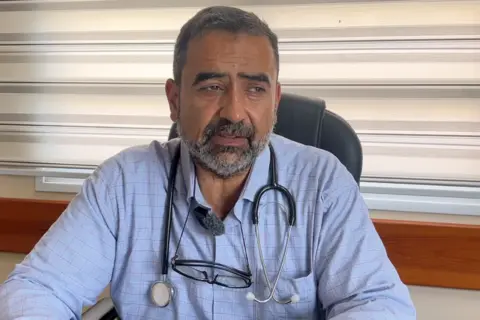 A doctor is seen with stethoscope round his neck at his desk in a hospital in Gaza