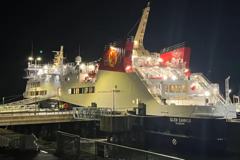 The Glen Sannox pictured moored at a dock under cover of darkness. The ship is well lit.