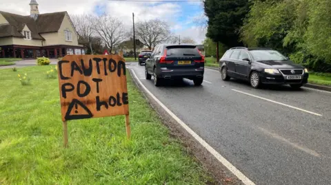 LDRS The sign reads 'caution pothole' on the side of the road to make drivers aware potholes are on the road