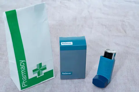 Getty Images A paper pharmacy bag, an inhaler box, and asthma inhaler.