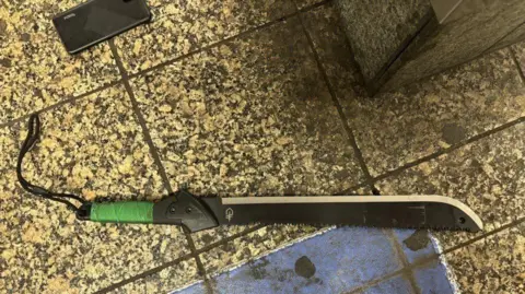 A black machete lies on the train platform.
