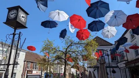 Driffield town centre on a sunny day, there are red, white and blue umbrellas installed outside the Market Place square. 