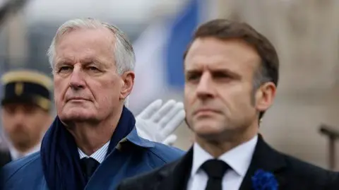 This Getty image shows former French President Emmanuel Macron, right, and French Prime Minister Michel Barnier, left, standing at attention during commemorations of the 106th anniversary of the Armistice of November 11, 1918, which ended World War I, in Paris. On November 11, 2024