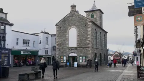 Keswick high street. The tourist information centre is located inside Moot Hall, an old stone building, which stands in the middle of the high street.