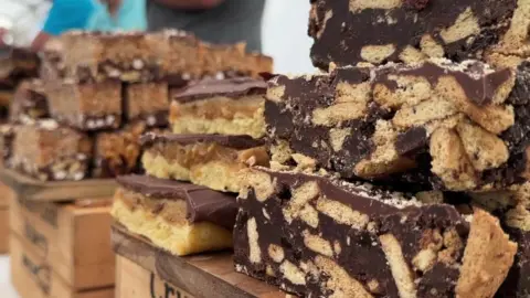 A selection of chocolate based food goods in a pile on wooden boxes.