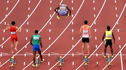 Noah Lyles jumps in the air on the start line for the 100m heats at the World Athletics Championships in Tokyo