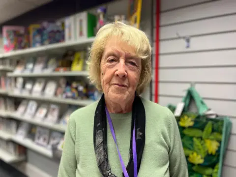 Pauline Marybell pictured wearing a green long-sleeve top and a black scarf