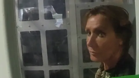GMP A forlorn-looking woman in the back of a police van