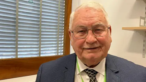 Man with suit in front of window.