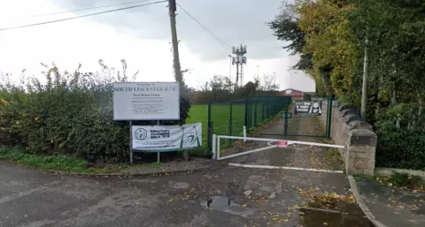 Google A gate road leading past a field to a rugby club