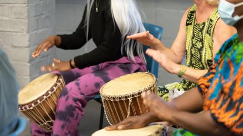A group of participants sat in a circle playing djembe drums