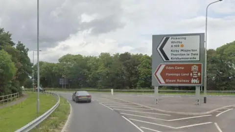 The junction of the A169 and A64. There is a road sign directing drivers to Pickering and Whitby on the right hand side of the road.