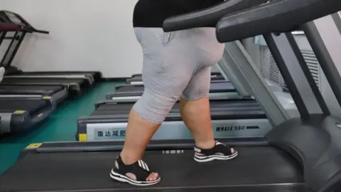 Getty Images An overweight pistillate   wearing grey shorts and a achromatic  t-shirt walks connected  a treadmill