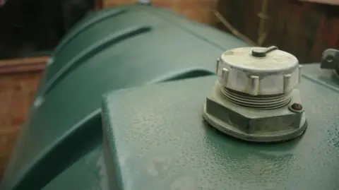 A close up view of a green screw-on cap on a large green plastic tank.