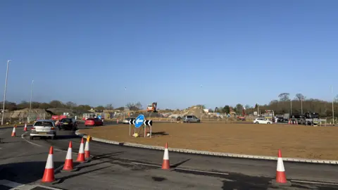 Luke Deal/BBC A general view of a brand new roundabout that has been constructed. Vehicles travel around the roundabout. Some cones have been placed on the roundabout blocking the outside lane. 