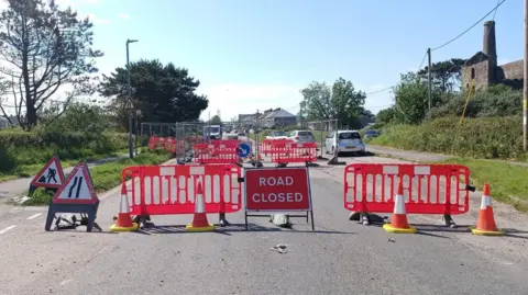 Cornwall Council Road closure signs, fences and cones in place on a road.